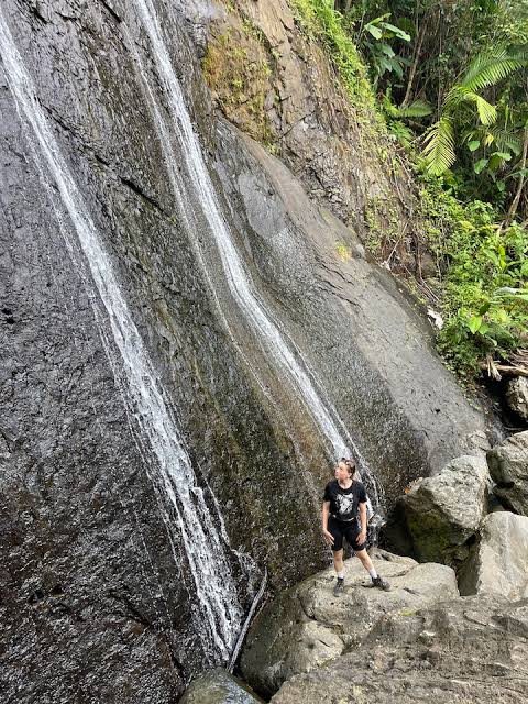 Cascada alta que cae por una pared de roca con una persona al pie