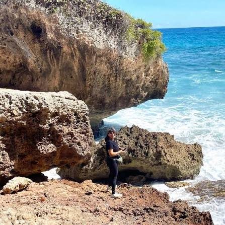 Costa rocosa con olas y una persona de pie sobre las rocas